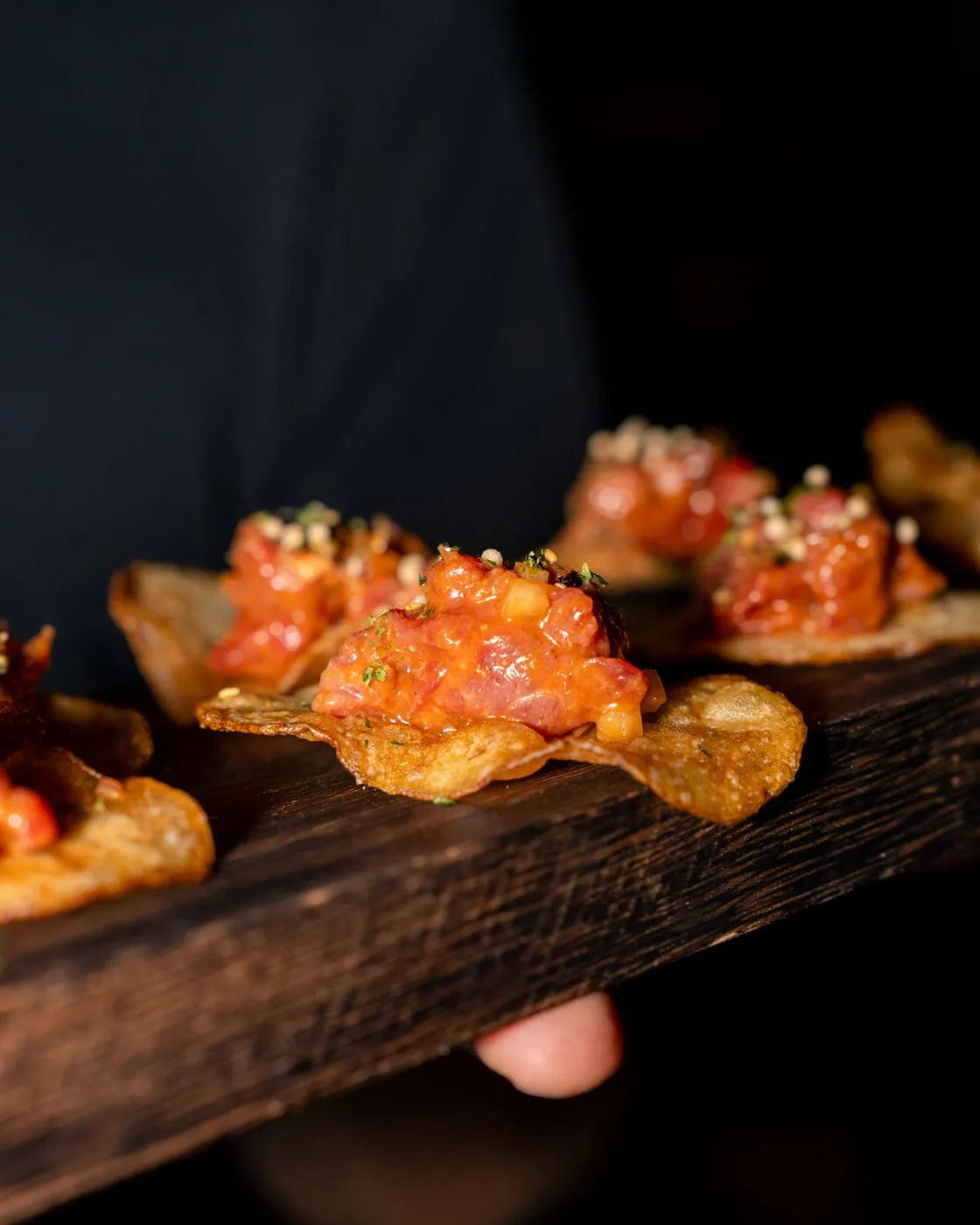 Tuna tartare spooned onto house potato chips and passed on a charred board